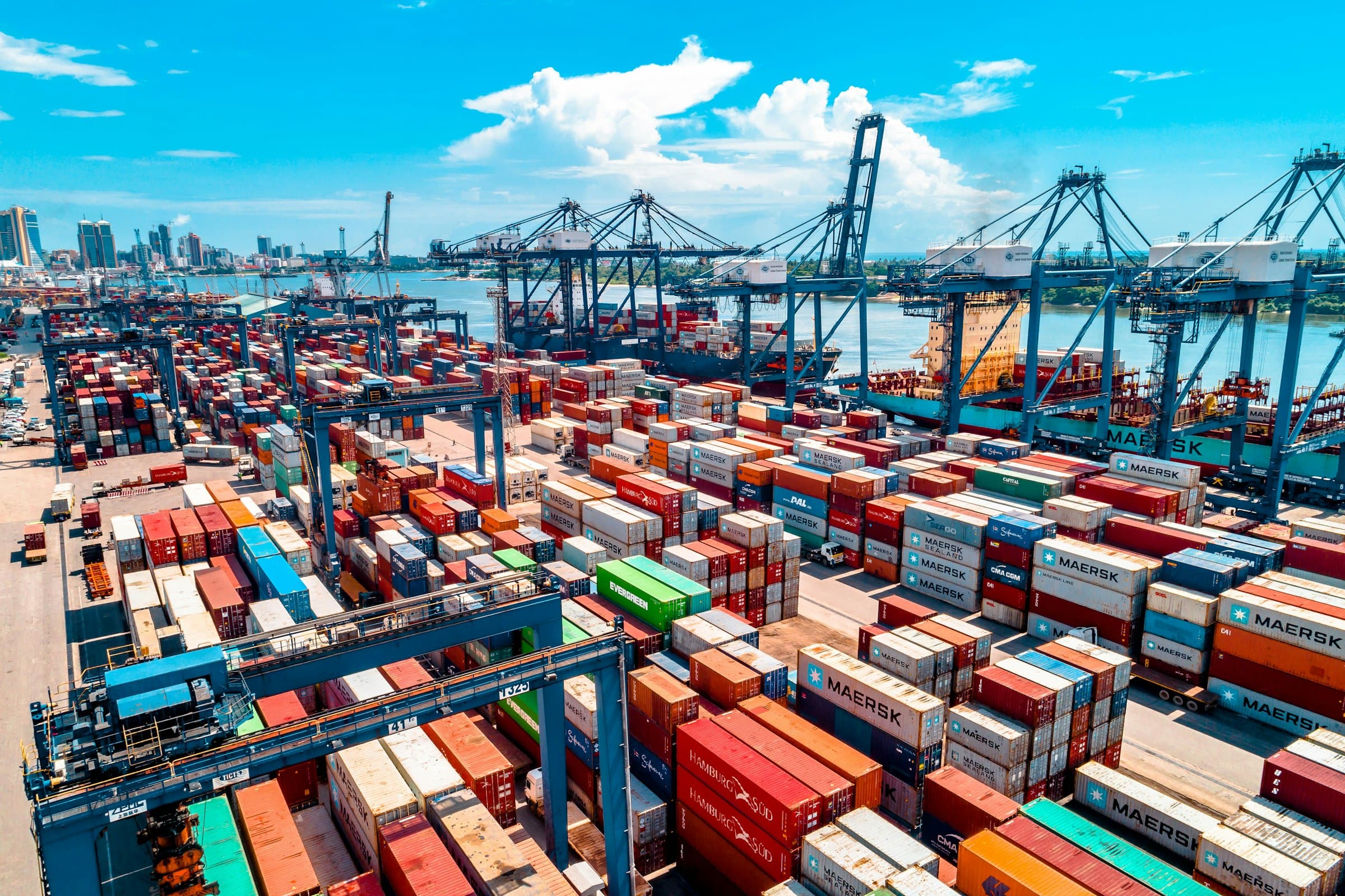 Stacked shipping containers and cranes at a container port