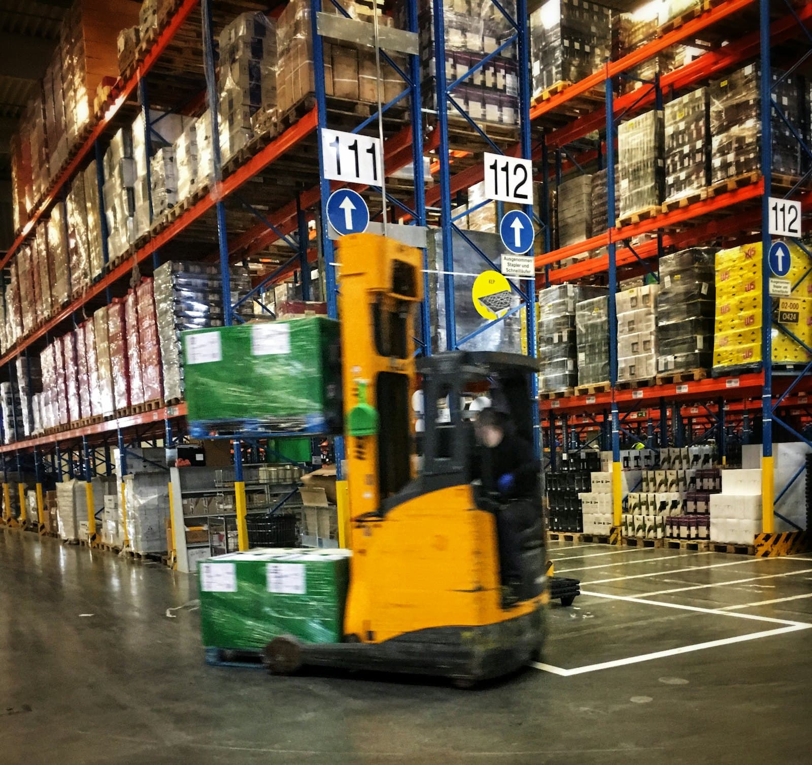 A forklift moving goods between warehouse racks